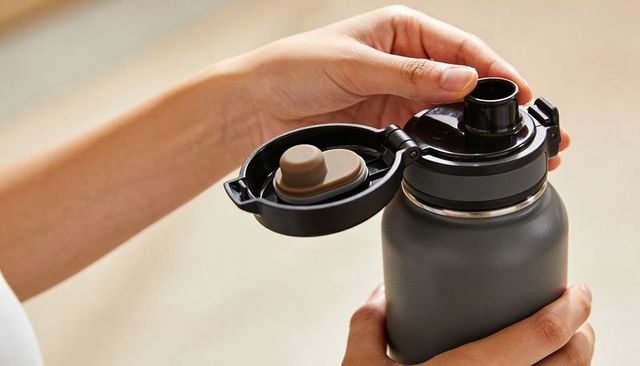 Opening insulated water bottle with flip lid closeup showing rubber stopper and spout