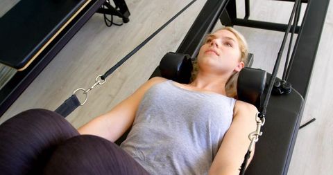Woman doing Pilates reformer workout focusing on core strength, flexibility and balance