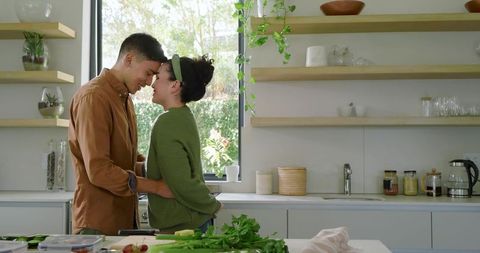 Couple Embracing in Modern Kitchen with Fresh Vegetables