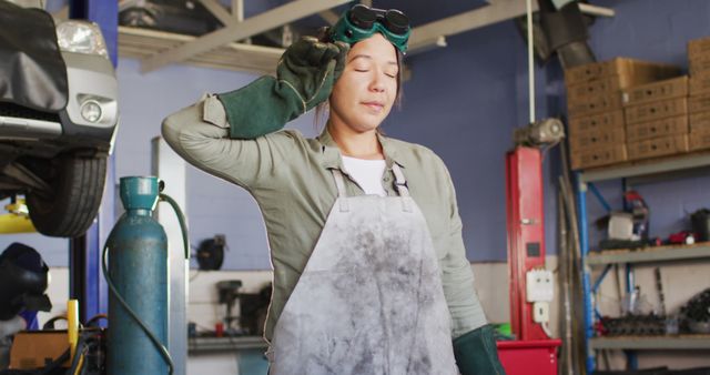 Female Auto Mechanic Resting in Busy Garage Wearing Protective Gear - Download Free Stock Images Pikwizard.com