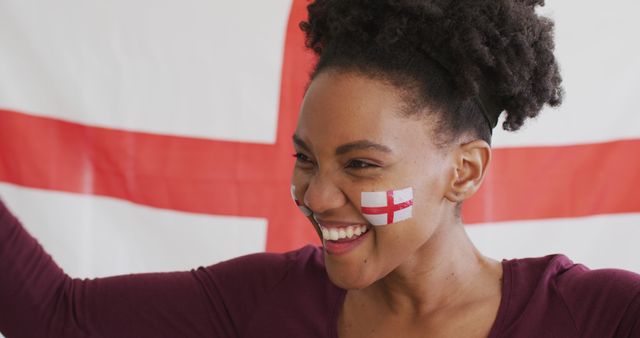 Woman with face painted with England flag enthusiastically cheering. Perfect for concepts of national pride, sports events, football tournaments, and spirited celebrations.