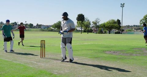 Adult cricket batter standing at crease in sunny suburban park