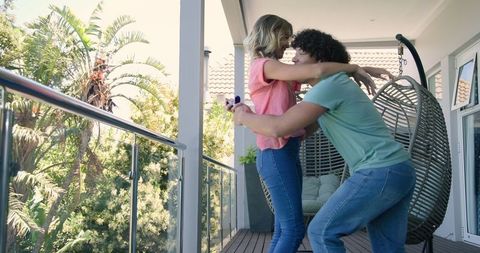 Young Couple Embracing on Sunlit Balcony Enjoying Togetherness