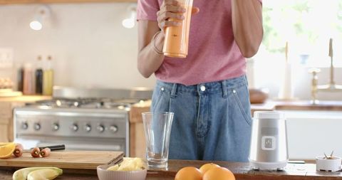 Healthy lifestyle: making fresh orange smoothie in cozy kitchen