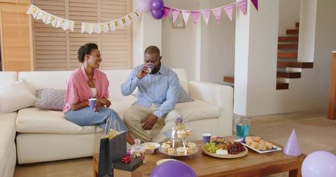 African American couple celebrating at-home birthday with cupcakes and purple balloons
