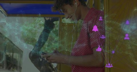 Urban young adult listening to music while using smartphone at bus shelter