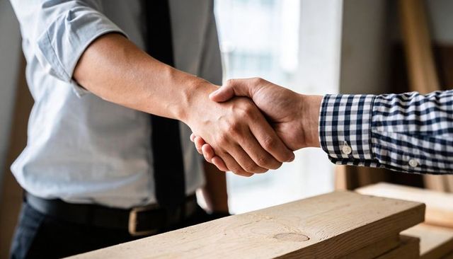 Business handshake over timber planks close-up contractor agreement and partnership