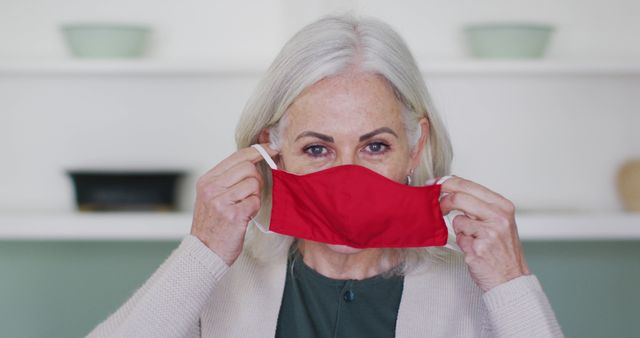 Senior Woman Putting On Red Face Mask - Download Free Stock Images Pikwizard.com