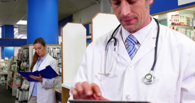 Pharmacist using digital tablet while colleague standing background in pharmacy 4k