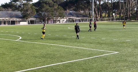 Amateur Soccer Match on Sunny Day with Players Passing Ball