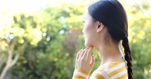 Asian Woman in Sunlit Garden Promoting Serenity and Wellness