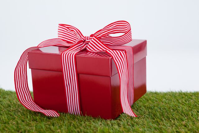 Red gift box on green grass against white background
