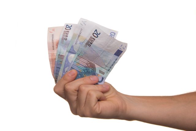Hand presenting multiple 20 euro bills symbols financial security and wealth. Ideal for websites and marketing materials related to banking, investment, and savings. Useful for articles on European economic topics or promotional material for financial services.