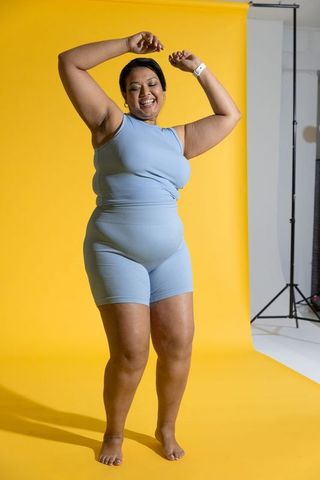 Confident plus-size asian woman dancing in blue activewear on vibrant yellow backdrop
