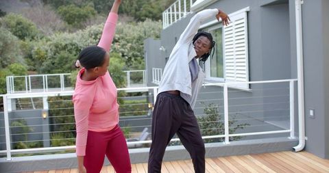 African American Couple Stretching on Home Deck During Outdoor Morning Fitness Routine