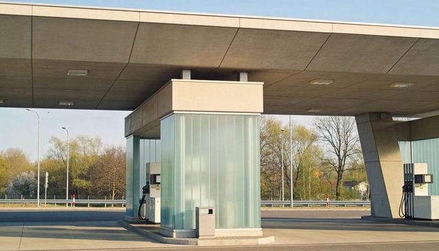 Glass-clad fuel island featuring concrete canopy and self-service pumps