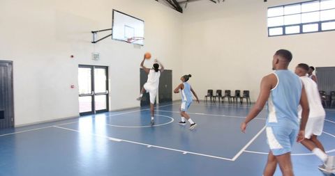 Basketball Players Engaging in Energetic Game on Indoor Court