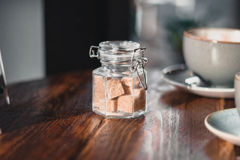 Glass jar of brown sugar cubes on wooden table