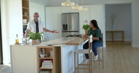 Couple chatting at kitchen island in modern open-plan home with bright minimalist interior