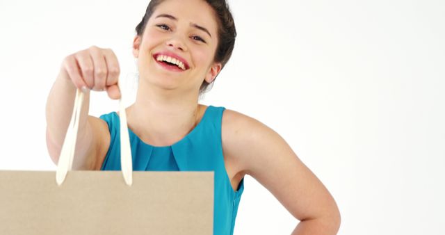 Young woman smiling while holding a shopping bag, perfect for themes related to retail, consumerism, and happiness. Can be used for promoting sales, shopping deals, or branding for retail stores.
