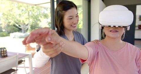 Elderly woman using vr for physical therapy at home with therapist support