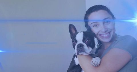 Smiling Woman Cuddling Boston Terrier in Modern Setting with Blue Flare