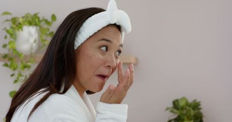 Woman Applying Eye Cream in Cozy Skincare Routine