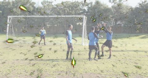 Youth soccer team celebrating goal near goalkeeper with dynamic light streak visual effect