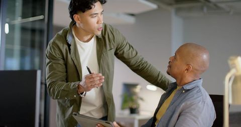 Asian and african american coworkers discussing tablet while pointing with pen in office