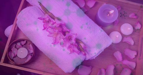 Tranquil spa with candles, towels and gladiolus flowers in pink hue