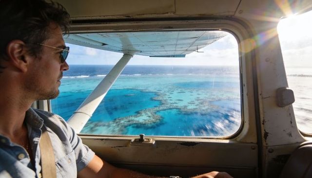 Male passenger gazing through small-plane window over turquoise coral reef and lagoon