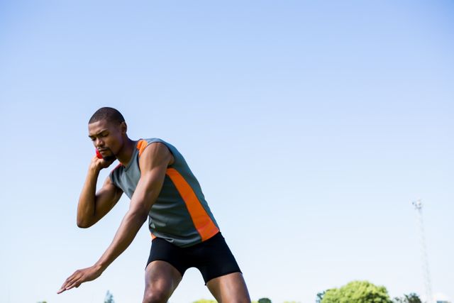 Athlete preparing to throw shot put ball in outdoor setting. Ideal for use in sports-related content, fitness and training programs, athletic competitions, and motivational materials.