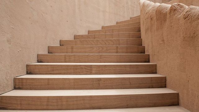 Ascending Minimalist Wooden Staircase with Curved Balustrade and Warm Beige Textures