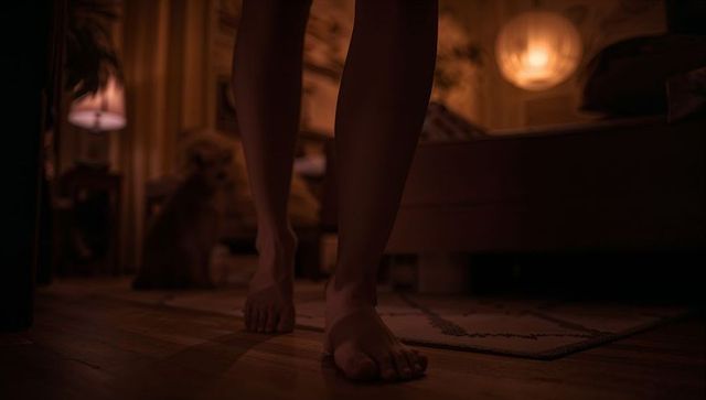 Barefoot walking on hardwood beside bed in warm cozy bedroom at night