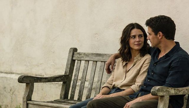 Couple sharing quiet moment on weathered wooden bench, intimate outdoor conversation