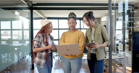 Diverse Female Coworkers Brainstorming Over Laptop and Tablet