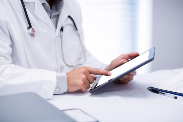Mid section of male doctor holding digital tablet in clinic