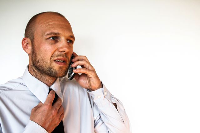 Businessman talking on phone while adjusting his tie. Ideal for illustrating workplace communication, business stress, or corporate environment. Suitable for business-related content, office scenarios, and articles on professional lifestyles or stress management.