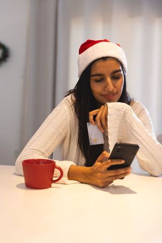 Festive woman online shopping in santa hat during holidays