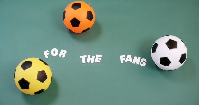 Colorful soccer balls arranged on green surface with 'For the Fans' text in white letters. Can be used for sports-related promotions, fan engagement campaigns, and community support initiatives.