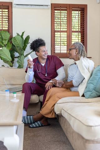 Home nurse visit showing diverse caregiver consulting senior african american woman