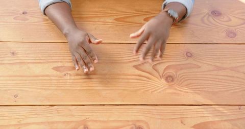 African American Hands with Wristwatch on Wooden Table