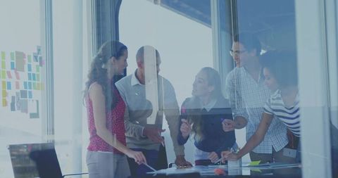 Diverse team collaborating around glass conference table brainstorming with sticky notes