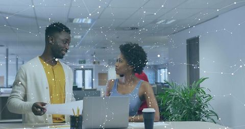 Professionals collaborating over laptop in modern office with digital network overlay