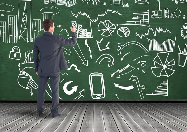 Businessman Drawing On A Green Chalkboard Covered With Diagrams and Graphs - Download Free Stock Photos Pikwizard.com