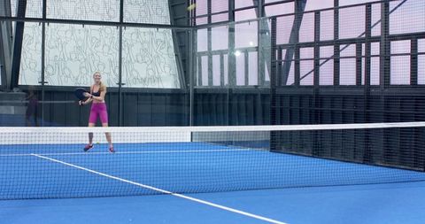 Woman Playing on Padel Court with Glass in Modern Setting