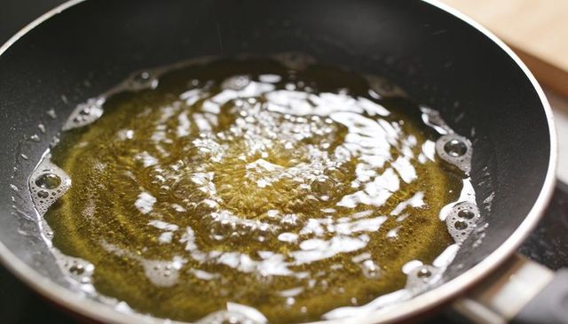 Sizzling oil bubbling in nonstick skillet on stove top close-up