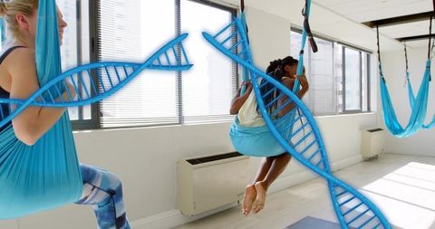 Practicing aerial yoga in blue hammocks with digital DNA helix overlay conveying wellness