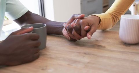 Diverse couple connecting with warm beverages at kitchen table