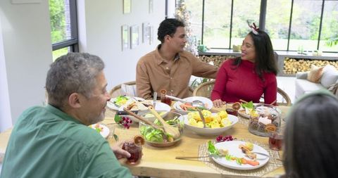 Multigenerational Family Sharing Festive Holiday Meal Around Sunlit Wooden Dining Table